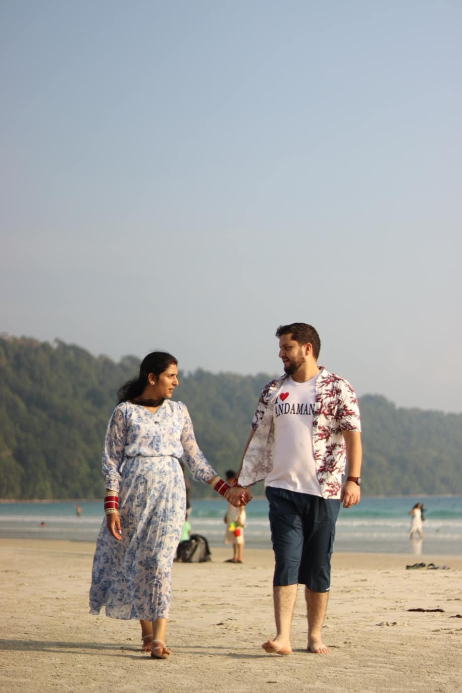 A couple walking hand in hand on the beach, one in an I-love-Andaman shirt