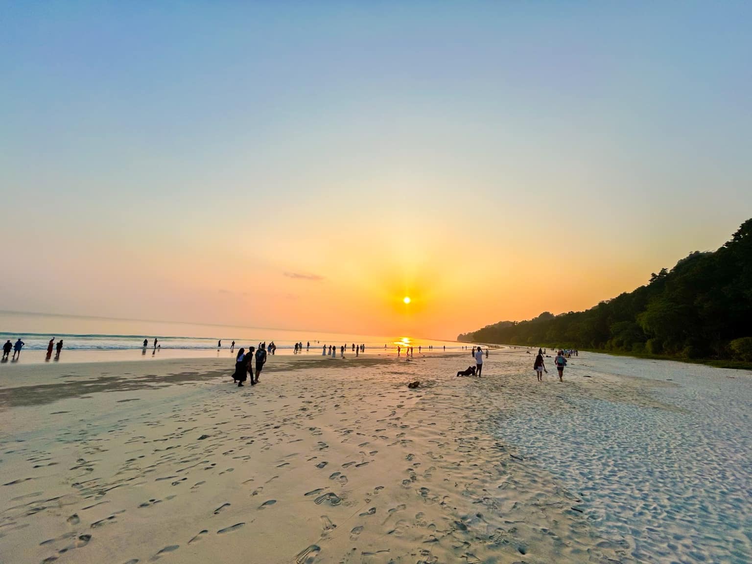 Sunset at Radhanagar Beach, Havelock, with visitors gathered along the waterline